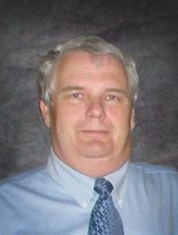 older man in blue shirt and tie with gray hair