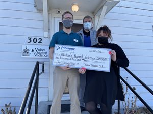 man and woman holding a large check, another man standing behind them, all wearing masks