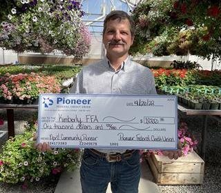 man holding check in front of plants