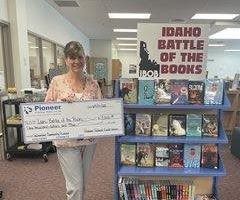 woman holding check next to book shelf