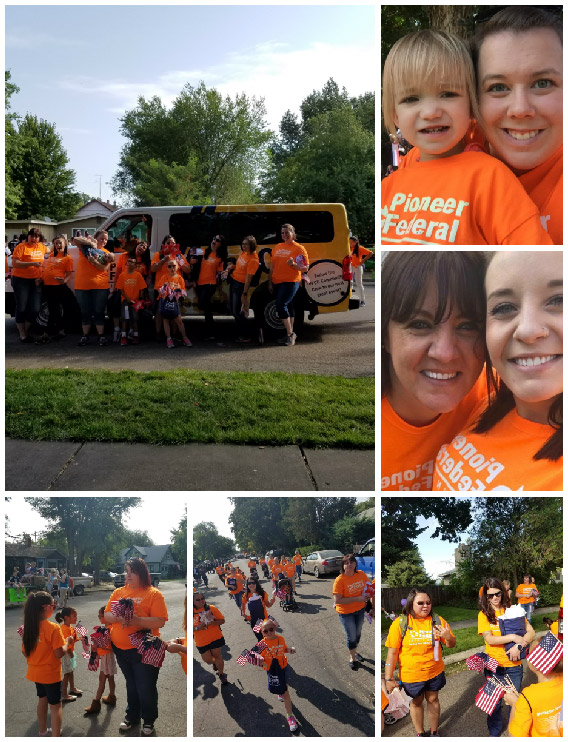 Pioneer volunteers in orange shirts participating in a parade, handing out US flags