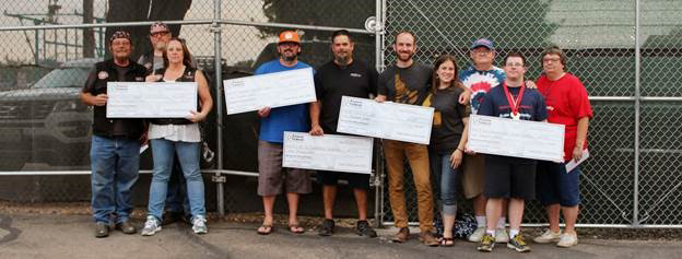Several different people holding giant checks they won from Pioneer at a baseball game