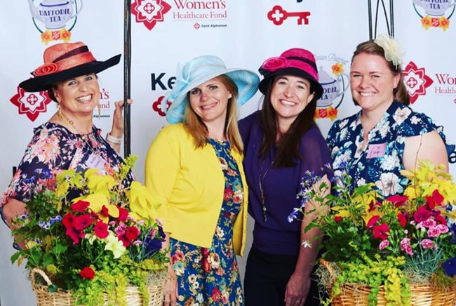 Women dressed for afternoon tea with large hats and flowery dresses