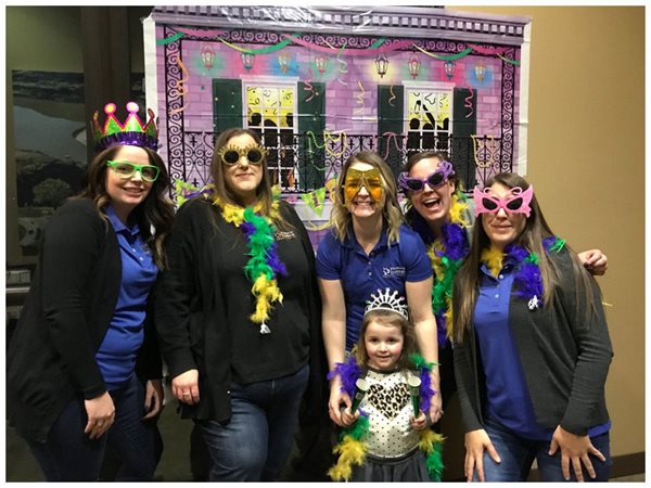 Pioneer employees wearing outrageous sunglasses in front of a party backdrop