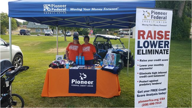 Two Pioneer employees standing behind a Pioneer booth covered in swag