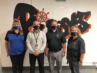 four adults all wearing facemasks
