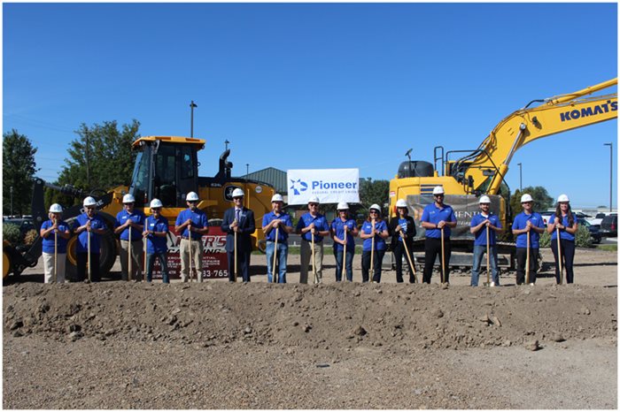 Ground breaking with people lined up holding shovels and wearing hard hats