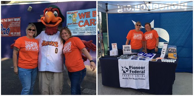 Pioneer employees at a Hawks game with a booth and posing with a mascot