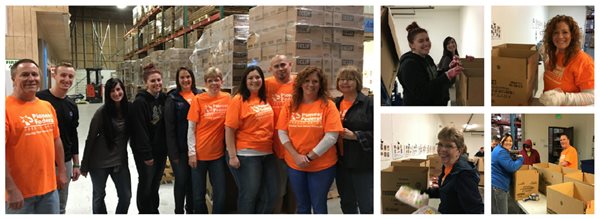 Pioneer volunteers in orange shirts working in a food bank full of cardboard boxes