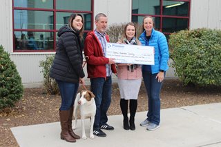 four people holding a giant check with a dog