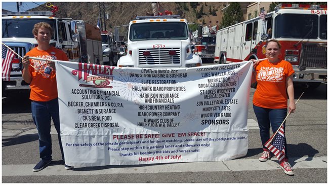 two pioneer volunteers holding a large sign for Hailey Idaho businesses in a parade