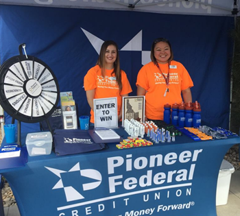 Two Pioneer employees standing behind a Pioneer booth covered in swag