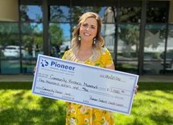woman in yellow dress holding a big check