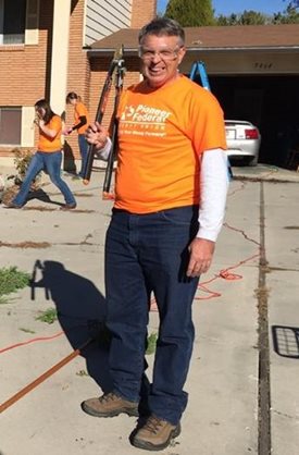 Man in orange volunteer shirt holding a large pair of clippers