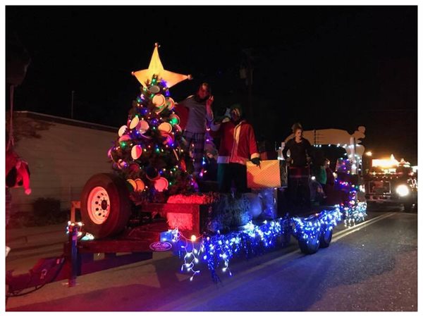 Parade float covered in Christmas lights and a Christmas tree on top