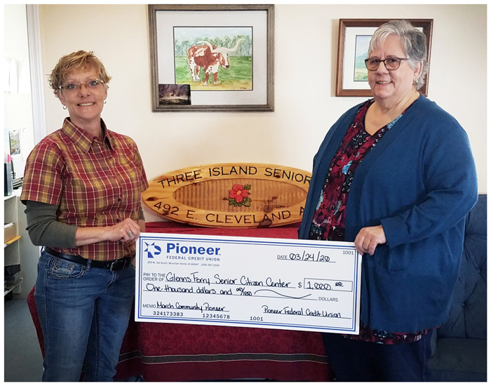 two women holding a large check for Community Pioneer