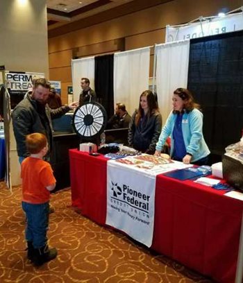 Two employees running a booth with a father and son looking at their roulette wheel