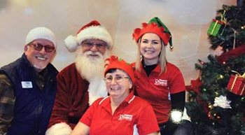 Pioneer employees dressed as elves posing with Santa