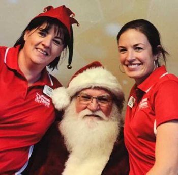 two Pioneer employees in red polos posing with Santa