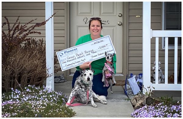 woman holding a big check with two dogs