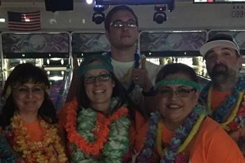 Five people posing in front of bowling lanes