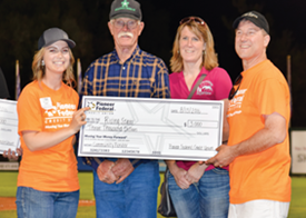 three smiling adults and one winner holding a giant check