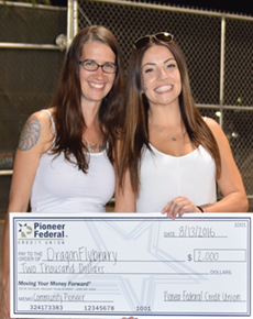 two smiling young women holding a giant check for two thousand dollars