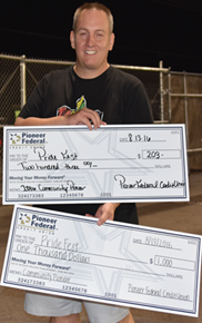 a middle age man holding two giant checks made out to Pride Fest