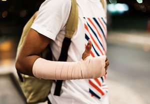 young man with cast around his arm giving a thumbs up