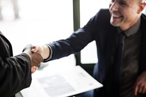 man shaking hands with another and smiling
