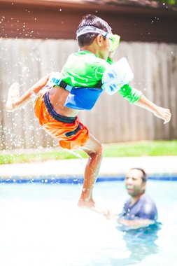 boy jumping into a swimming pool