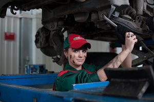 young woman working on a car covered in grease