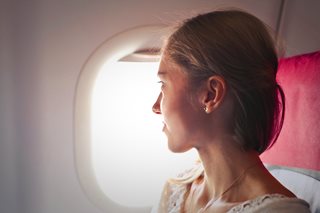 woman on a plane looking out a window