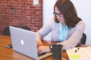 woman typing on macbook at a desk