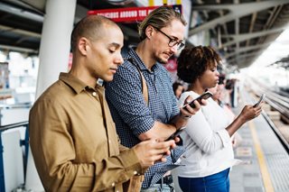 three adults all looking at their smart phones