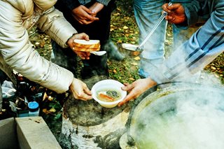 people holding a bowl of soup and bread
