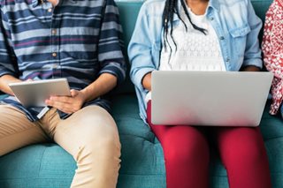 young man and woman sitting next to each other, woman looking at laptop, man looking at iPad