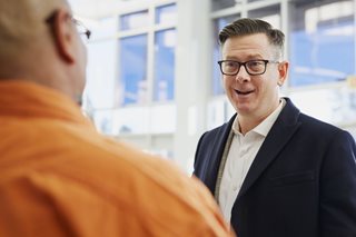 older man in a suit talking to another guy