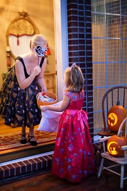 small girl in a dress trick or treating at a home
