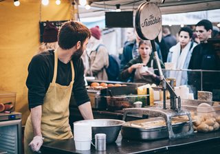 man cooking food in a booth at a farmer's market