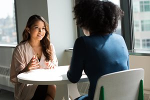 two women talking while sitting at a table