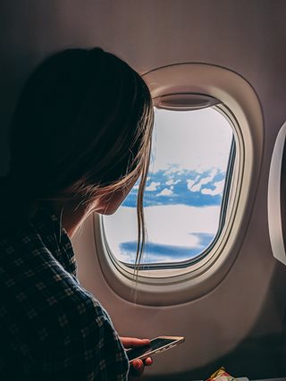 young woman looking out an airplane window