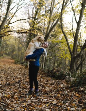 woman holding a dog in a forest
