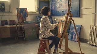 young black woman painting in an art studio