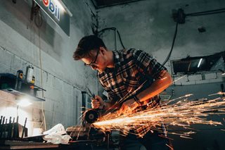 young man working with a metal grinder and sparks are flying out