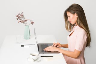 young woman sitting at a table working on a laptop