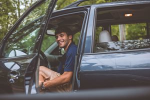 young man in a car with the door open