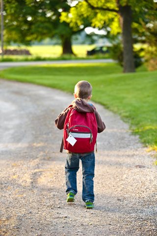 young kid walking away wearing a red backpack