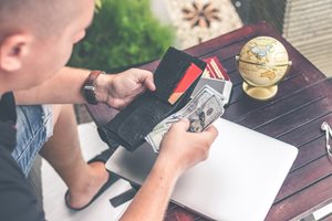 young man pulling out cash from his leather wallet