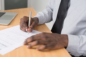 man writing on tax forms with a pen